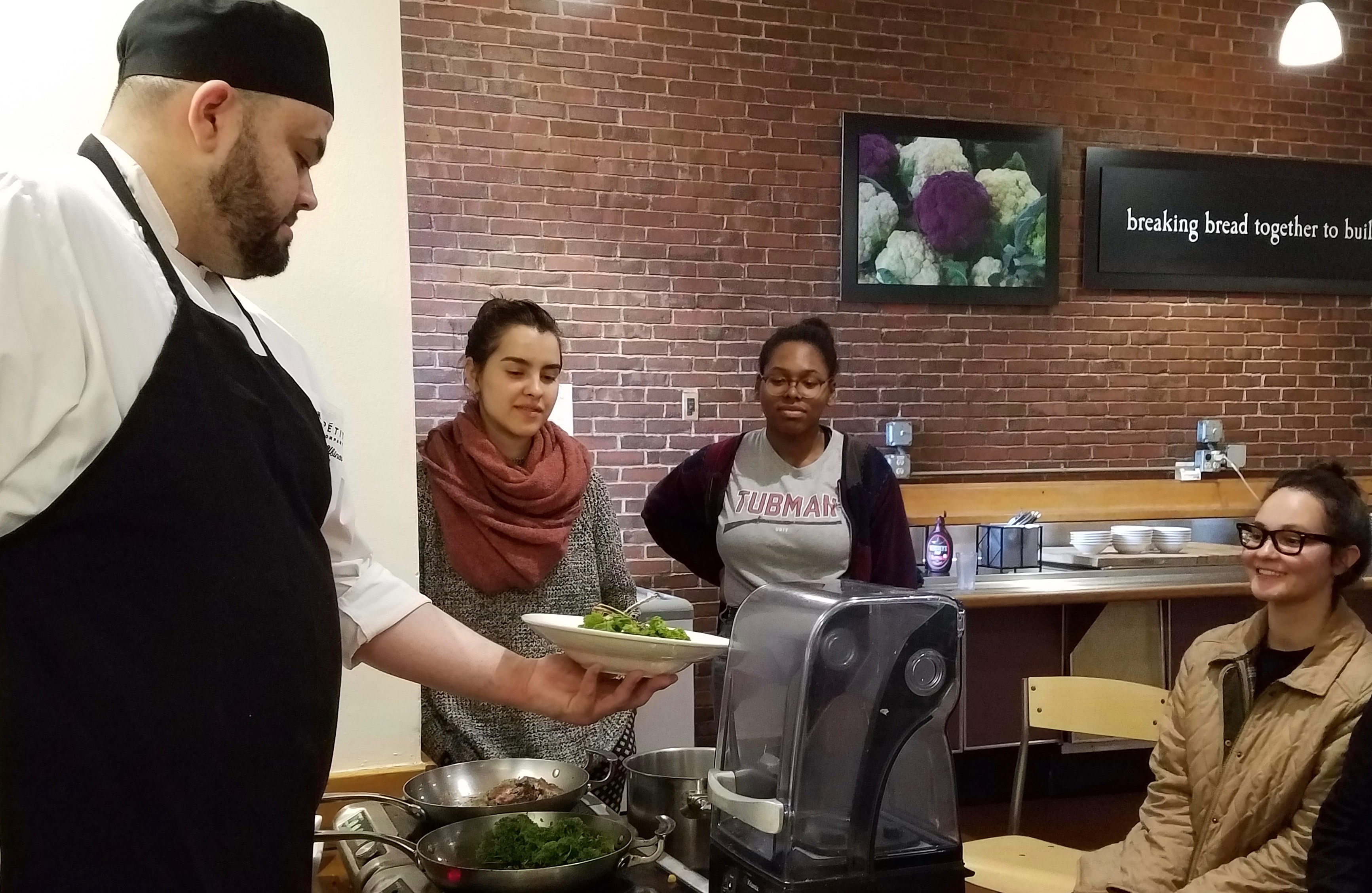 Chef showing plated food to 3 students