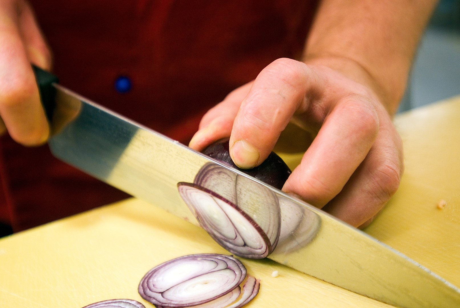 Hands with knife cutting onion