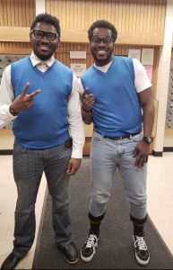 Two men dressed in matching blue vests for twins day