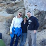 Glenna, student, and Earl pose in front of a rocky background