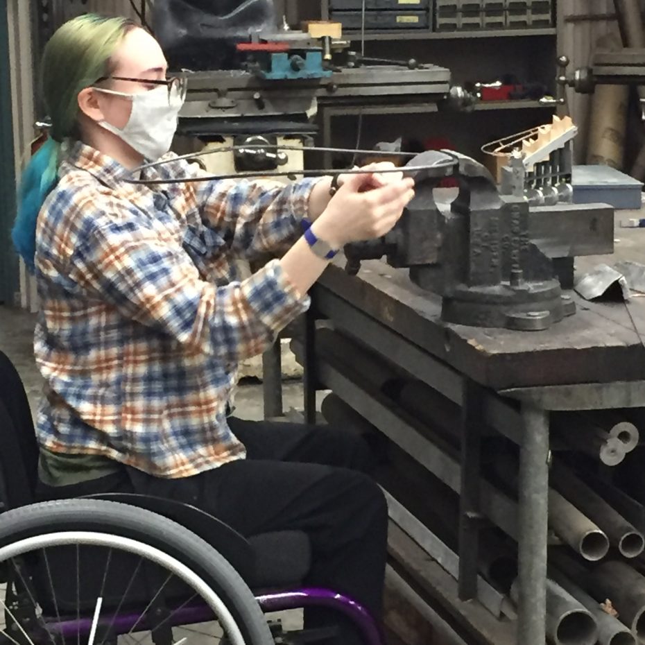 Student in wheelchair working at bench vise