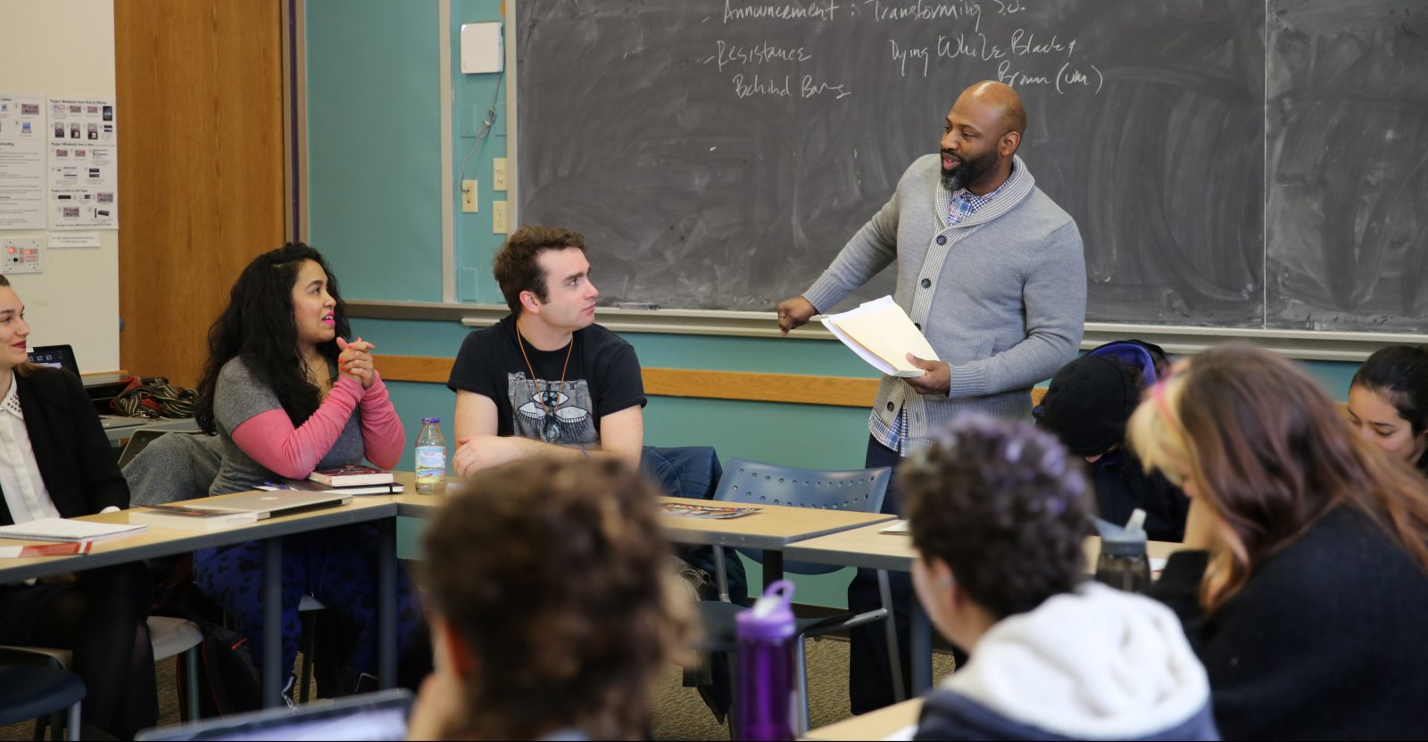 professor talks to class with blackboard