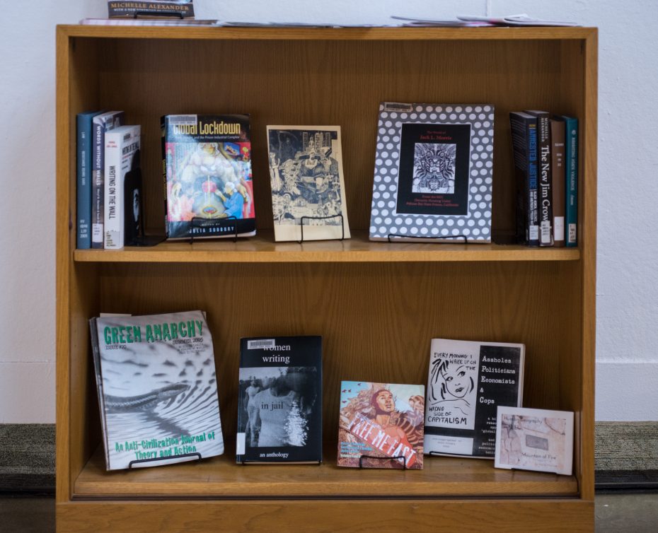 image: small bookcase with a variety of books related to the prison industrial complex in America