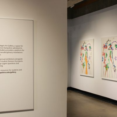 The rightmost half of the exhibition description describes Hampshire College's Art Gallery in the foreground while three lithographs by the artist Marisol hang on a gallery wall in the background with one only partially visible