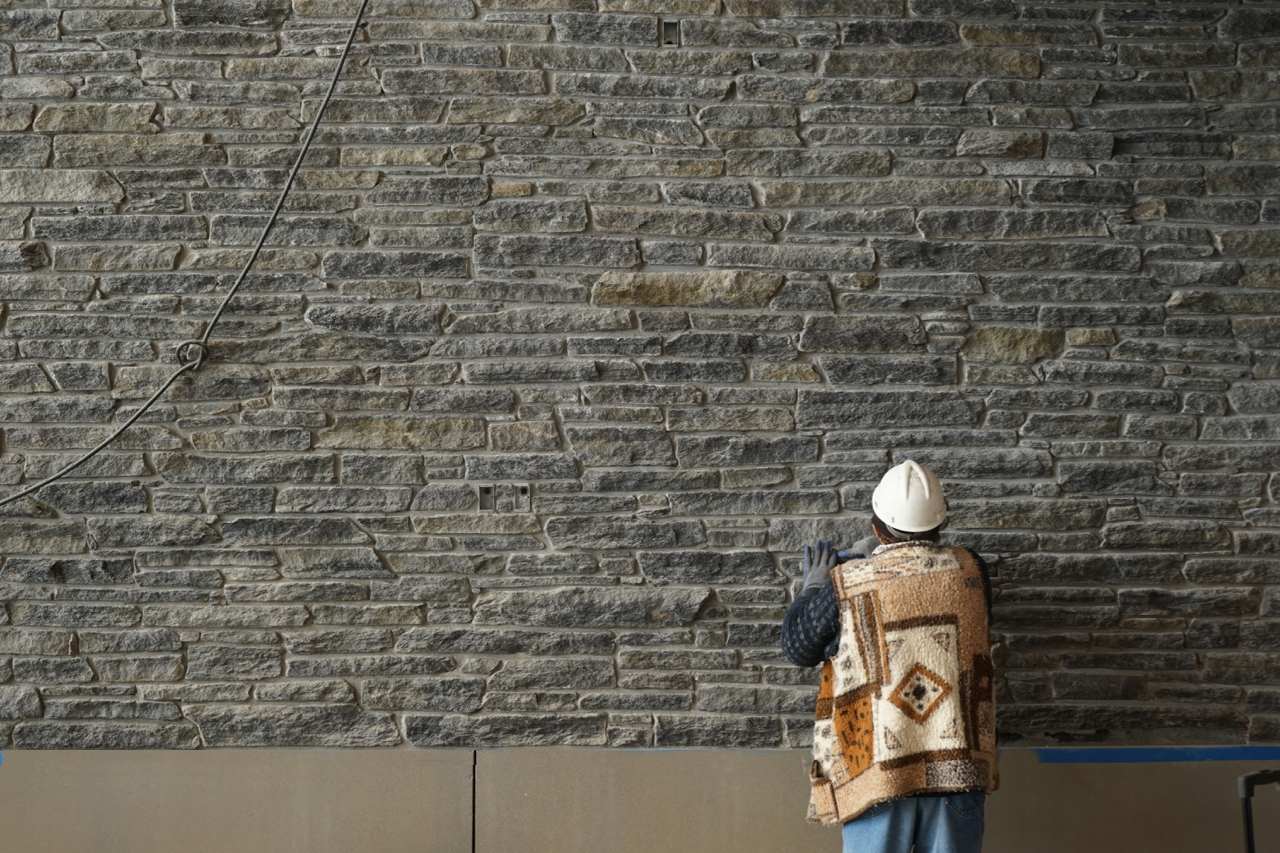 Stoneworker working on interior stone wall of the R.W. Kern Center.