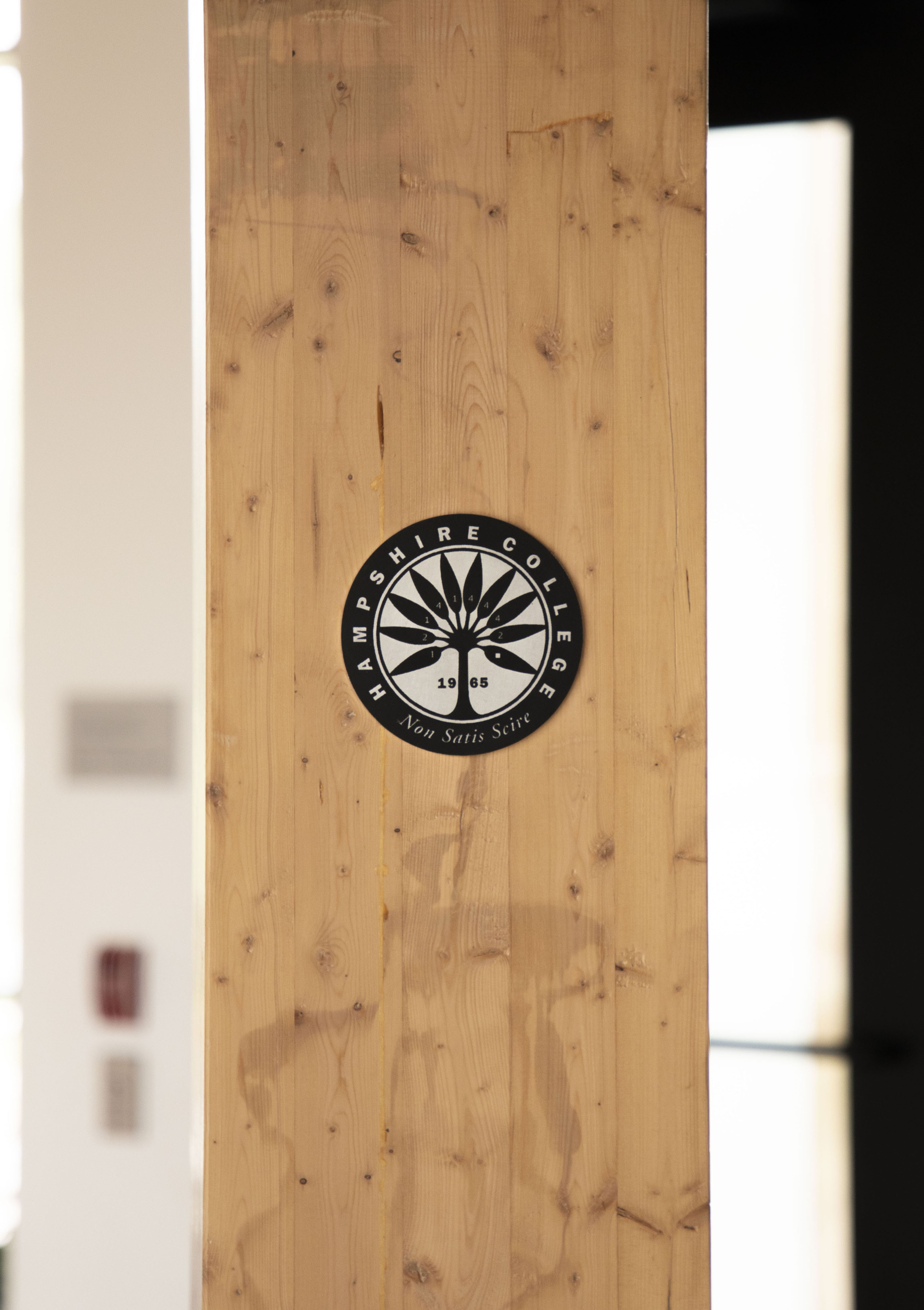 A wooden collum inside the R.W. Kern Center with the black and white Hampshire College logo on it.