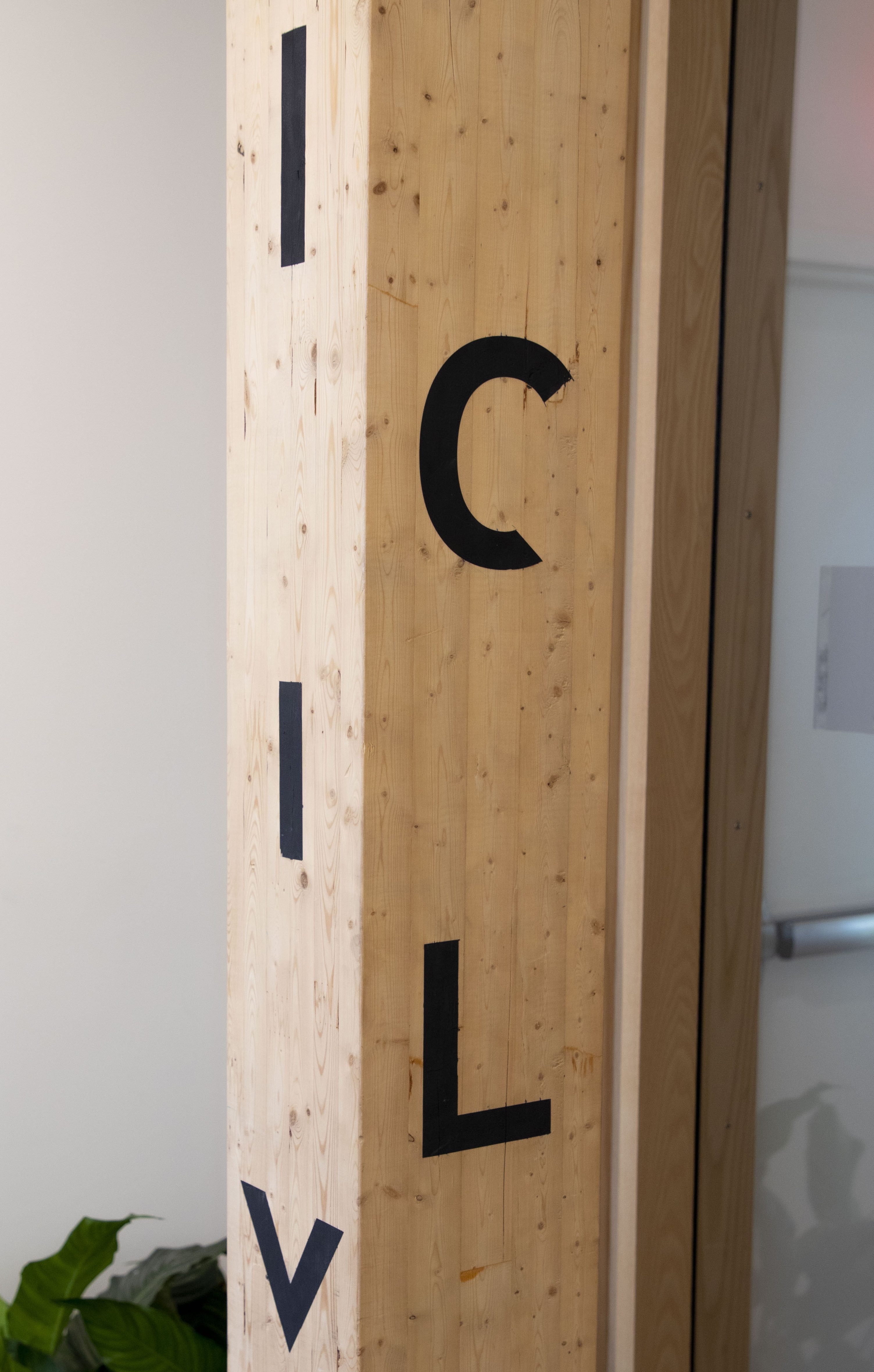 Timber column with black letters and shapes on it.