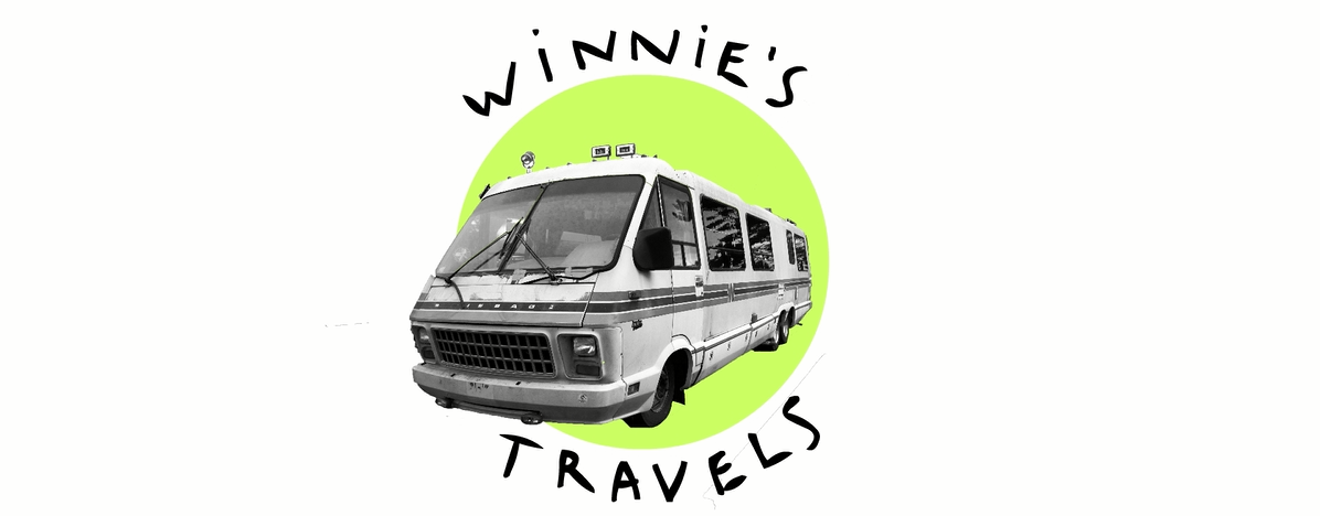 A green circle with a black and white photo of a travel bus. Two words bend around the green circle saying, "Winnie's Travels."