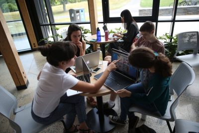 Students on computers around a wooden table at the R.W. Kern Center.