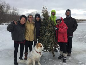 Students posing for a picture standing on a frozen pond with a dog