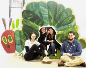 Students pose with image of Eric Carle Caterpillar