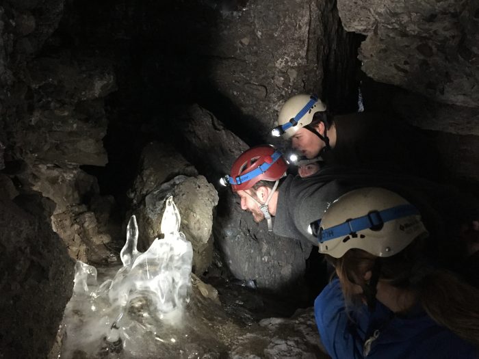 Students inside a cave looking at ice