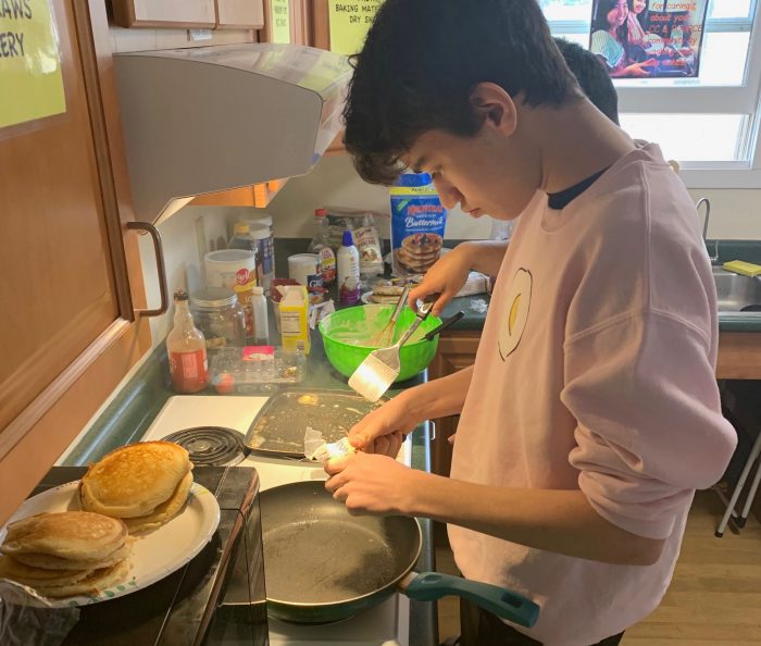 Student cooking pancakes in the Cultural Center